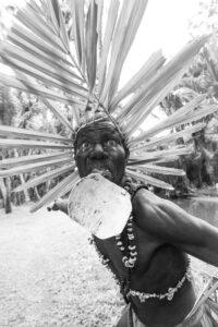 A man with a spear and a shell in his mouth.