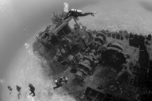 A scuba diver is diving over an underwater shipwreck.