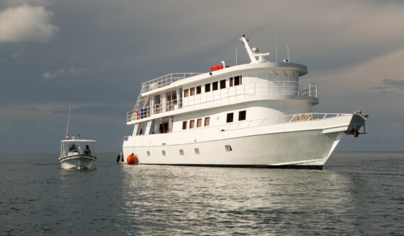 A white boat is in the water near another boat.