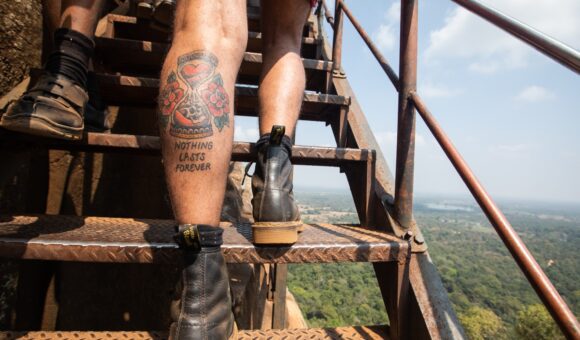 A person with tattoos is climbing up some stairs