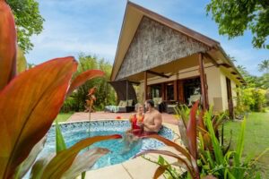 A man and woman sitting in the pool of their home.