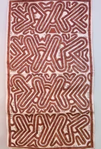 A geometric pattern mola textile in red and white.